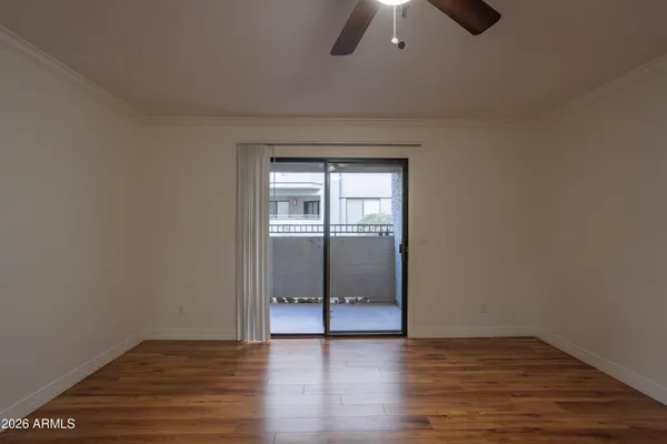 a view of an empty room with wooden floor and a window