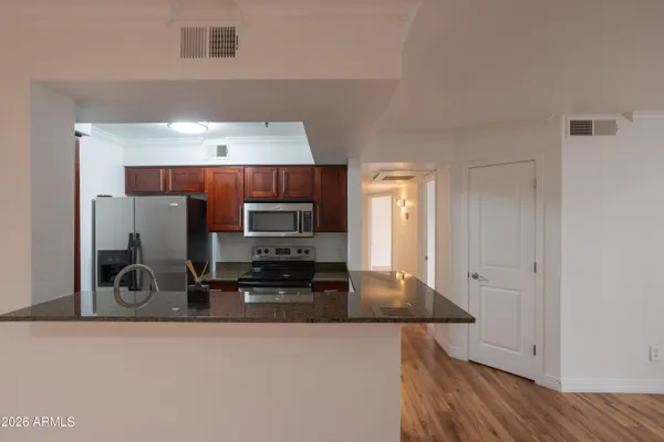 a kitchen with stainless steel appliances a sink a stove a microwave a refrigerator and cabinets