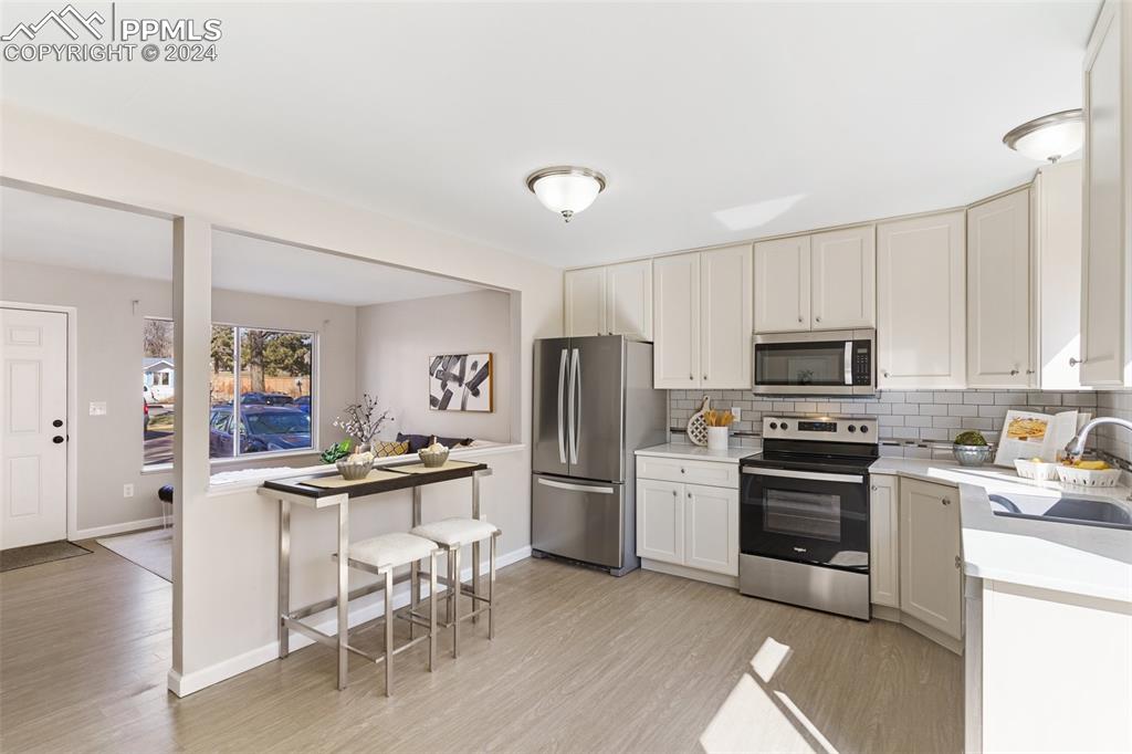 773 Alexander Road, Unit B Colorado Springs, CO 80909 - Photo 7 of 16 a kitchen with white cabinets and stainless steel appliances
