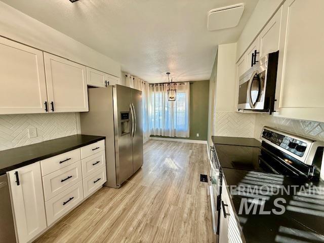 1139 Webster Street Clarkston, WA 99403 - Photo 11 of 34 Kitchen with tasteful backsplash, stainless steel appliances, white cabinets, and light wood-style floors
