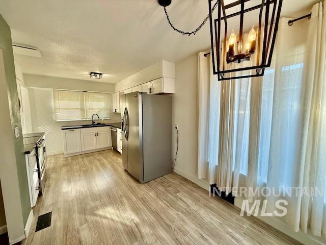 1139 Webster Street Clarkston, WA 99403 - Photo 12 of 34 Kitchen with stainless steel appliances, white cabinetry, light wood-type flooring, and dark countertops