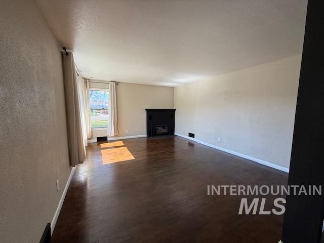 1139 Webster Street Clarkston, WA 99403 - Photo 9 of 34 Unfurnished living room with dark wood-type flooring, a fireplace, and a textured wall