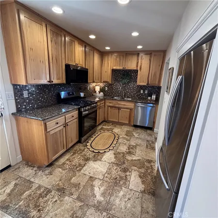 a kitchen with stainless steel appliances granite countertop a refrigerator and a stove top oven