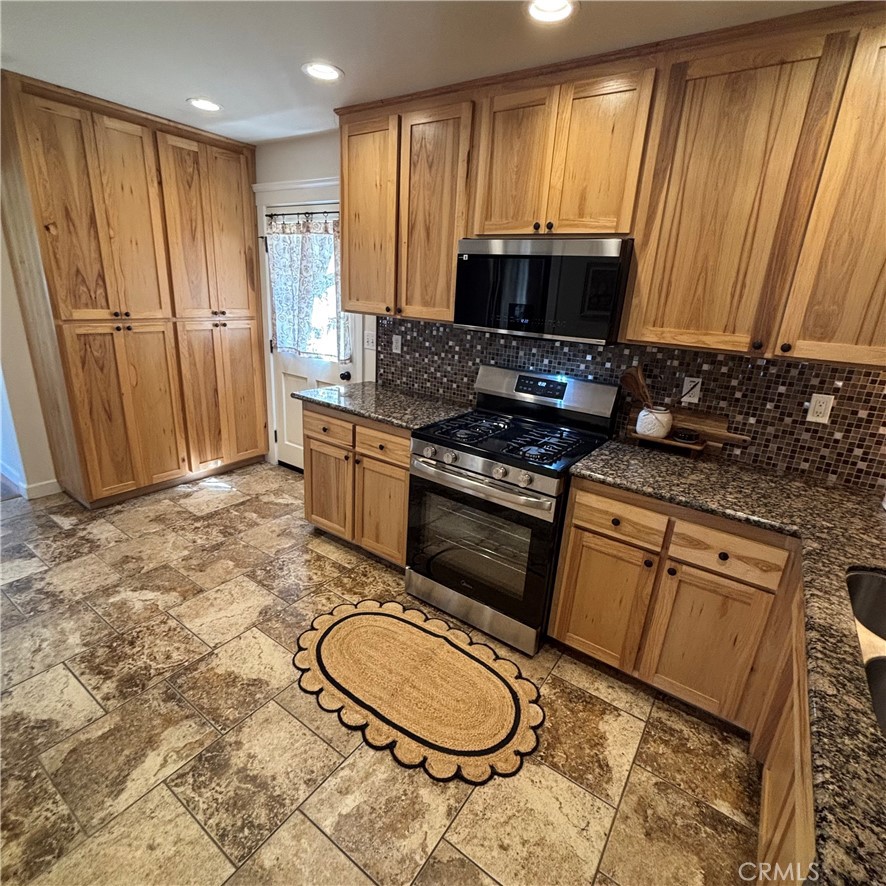 5012 Brockton Avenue Riverside, CA 92506 - Photo 22 of 28 a kitchen with stainless steel appliances granite countertop a stove a sink and a microwave