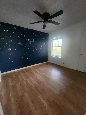 an empty room with a ceiling fan and window