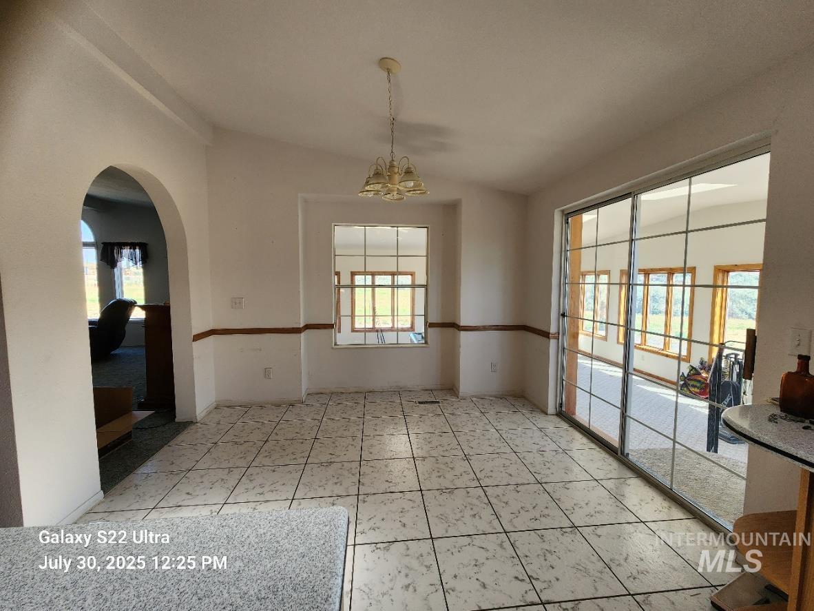 650 Ash Street Vale, OR 97918 - Photo 15 of 24 Empty room featuring a chandelier, healthy amount of natural light, arched walkways, and light tile patterned flooring