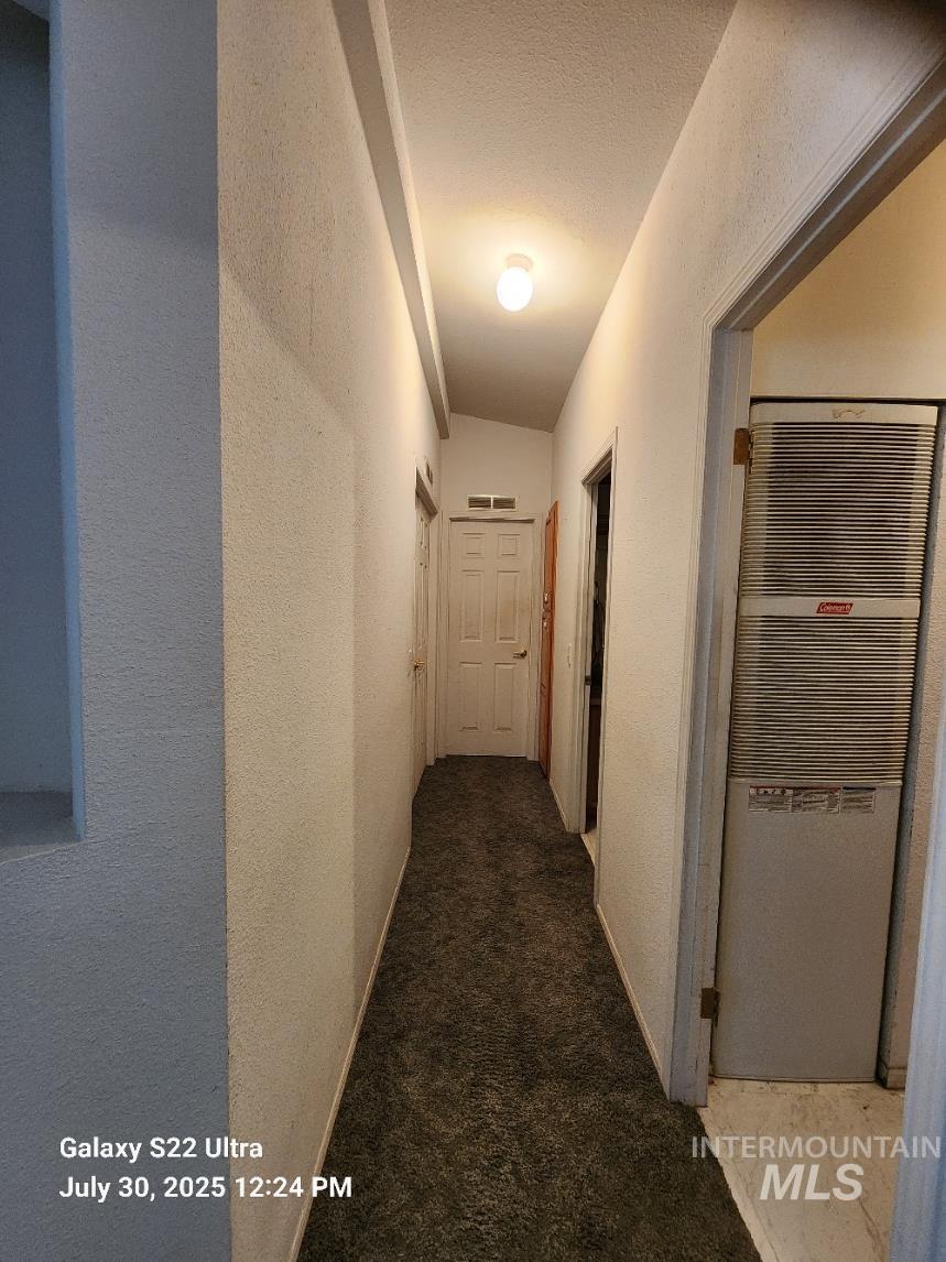 650 Ash Street Vale, OR 97918 - Photo 16 of 24 Hallway featuring a heating unit, carpet, a textured ceiling, and a textured wall