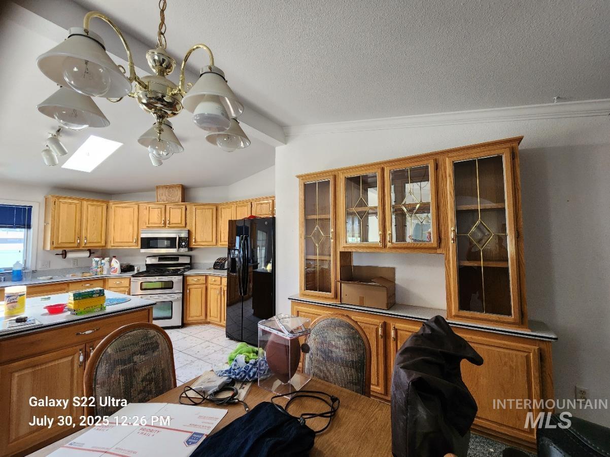 650 Ash Street Vale, OR 97918 - Photo 10 of 24 Kitchen featuring vaulted ceiling, stainless steel appliances, a skylight, glass insert cabinets, and crown molding