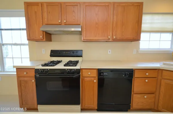 a kitchen with granite countertop a stove top oven cabinetry and a sink