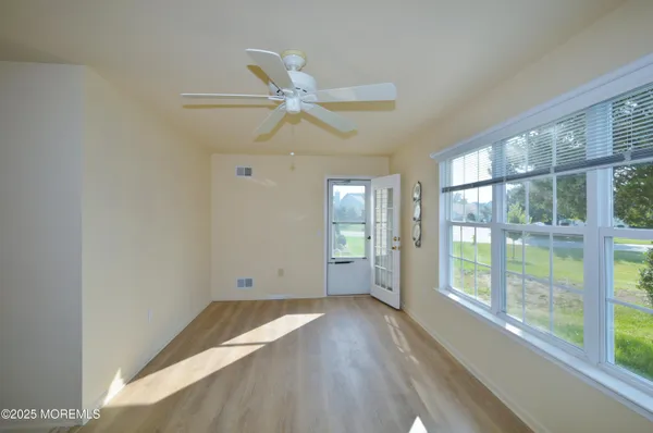 a view of empty room with wooden floor and fan