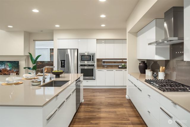 a large kitchen with stainless steel appliances lots of counter space and wooden floor