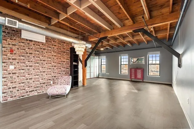 a view of an empty room with wooden floor and windows