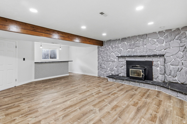 2693 Teal Way Sandy, UT 84093 - Photo 24 of 50 Spacious room featuring wood-finish flooring, a prominent stone fireplace with hearth, a built-in bar with a tile facade and countertop, and exposed wood beam accents