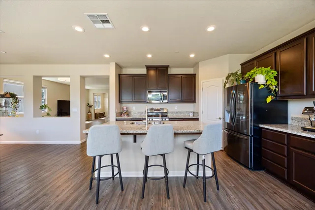 a kitchen with stainless steel appliances a dining table chairs stove refrigerator and cabinets