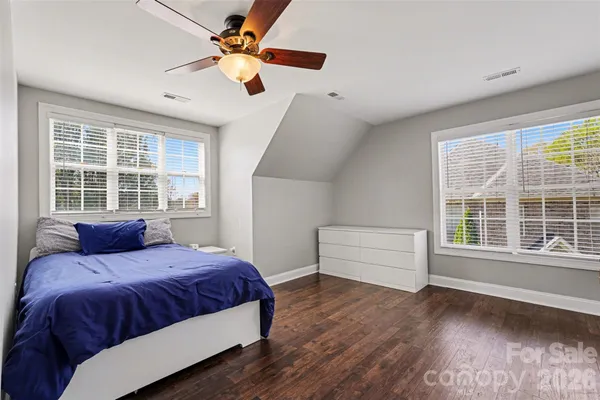a bedroom with a bed and a large window with wooden floor
