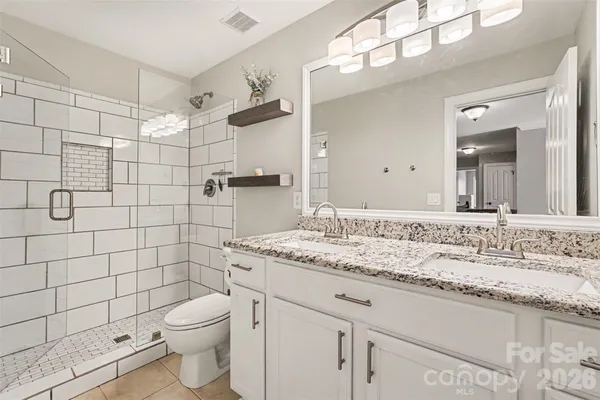 a bathroom with a granite countertop sink a toilet and shower