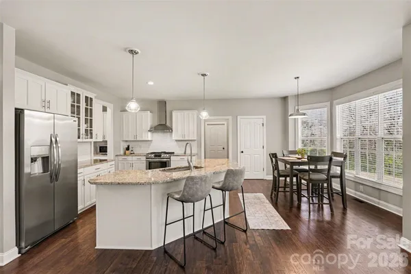 a kitchen with stainless steel appliances granite countertop a stove a refrigerator a kitchen island a dining table and chairs