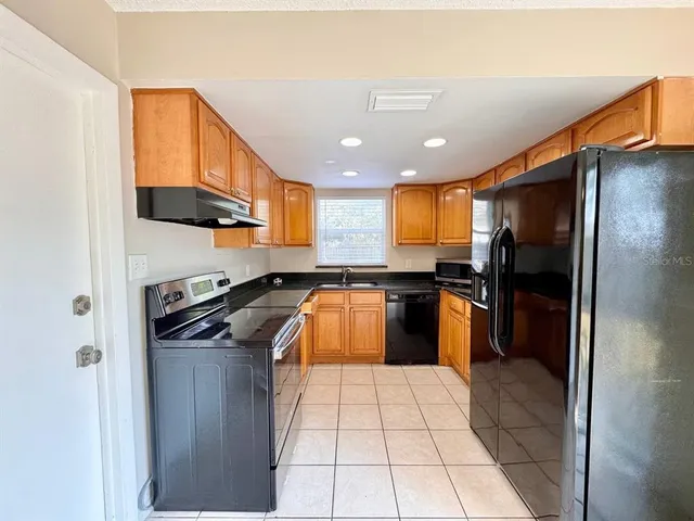 a kitchen with stainless steel appliances granite countertop a stove a sink and a refrigerator