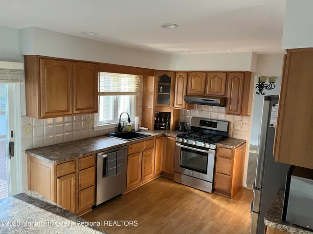 a kitchen with stainless steel appliances granite countertop a stove a sink dishwasher a refrigerator and a microwave