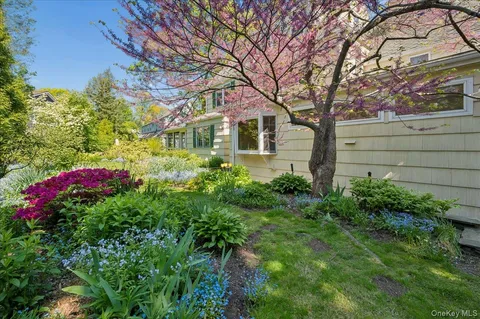 a front view of a house with plants and large trees