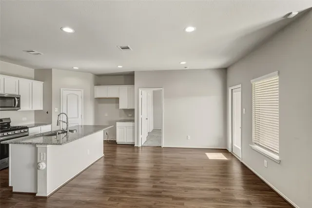 a large white kitchen with stainless steel appliances lots of counter space and wooden floors