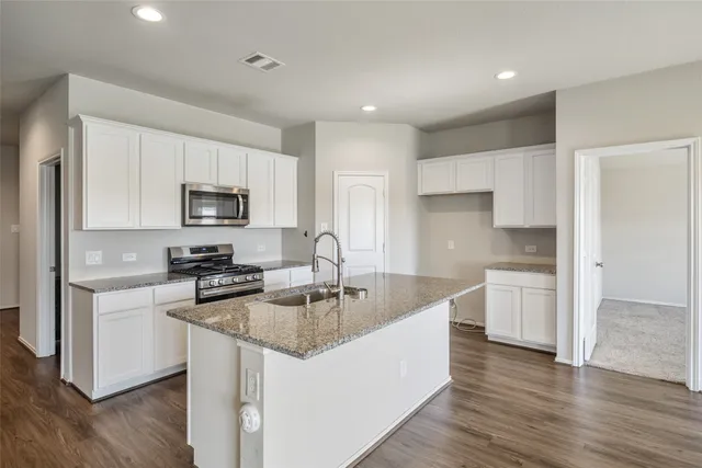 a kitchen with kitchen island white cabinets appliances and wooden floor