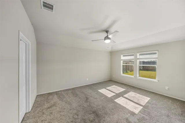 an empty room with windows and chandelier fan
