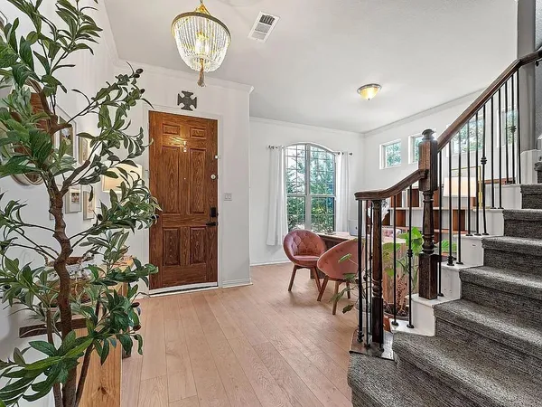 a view of a hallway with wooden floor windows a chandelier and a window