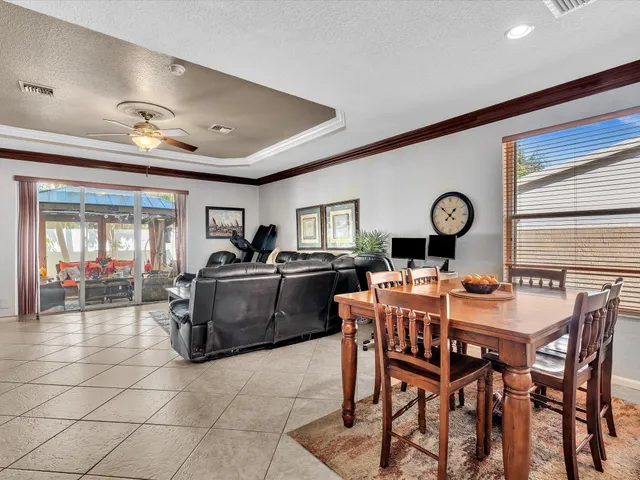 a living room with furniture a chandelier fan and a large window