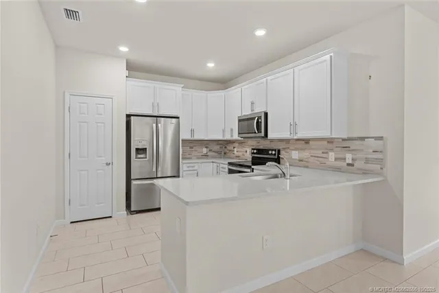 a kitchen with white cabinets and stainless steel appliances