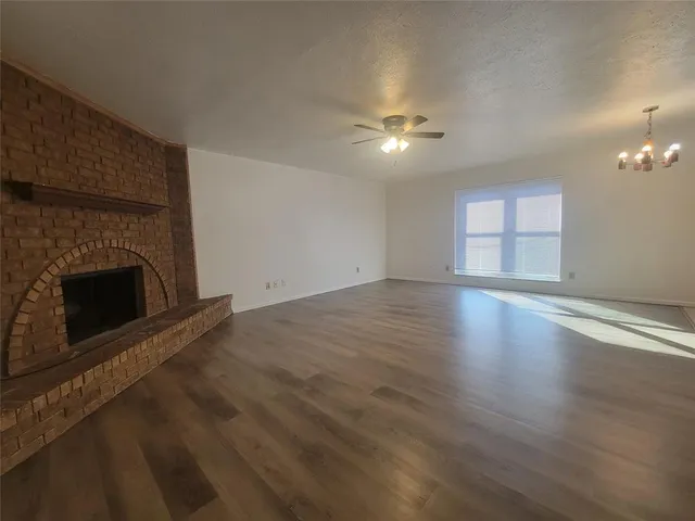 an empty room with wooden floor fireplace and windows
