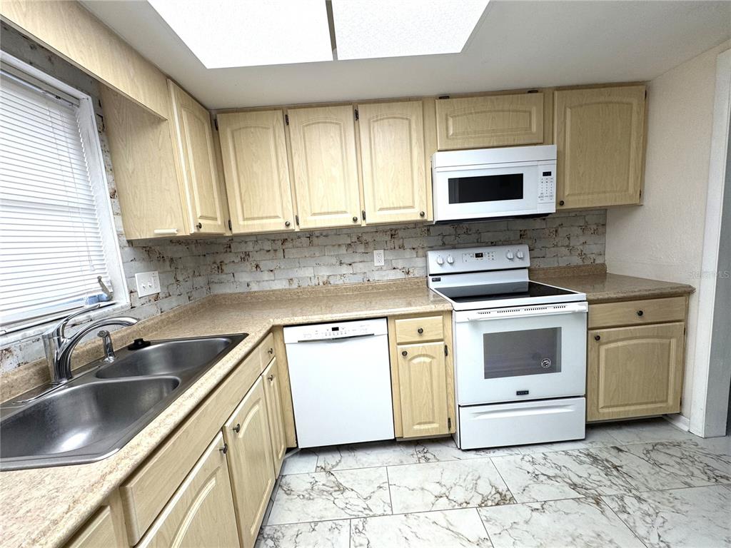 610 Indian Rocks Road North, Unit 103 Belleair Bluffs, FL 33770 - Photo 4 of 13 a kitchen with stainless steel appliances a stove sink and microwave