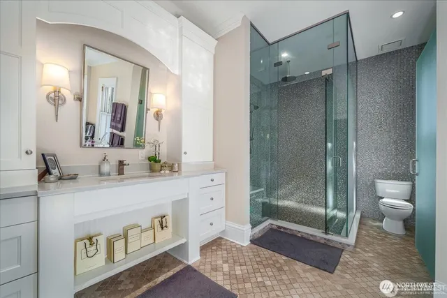 a bathroom with a granite countertop sink a toilet and shower