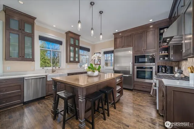 a kitchen with stainless steel appliances granite countertop a kitchen island hardwood floor sink and stove