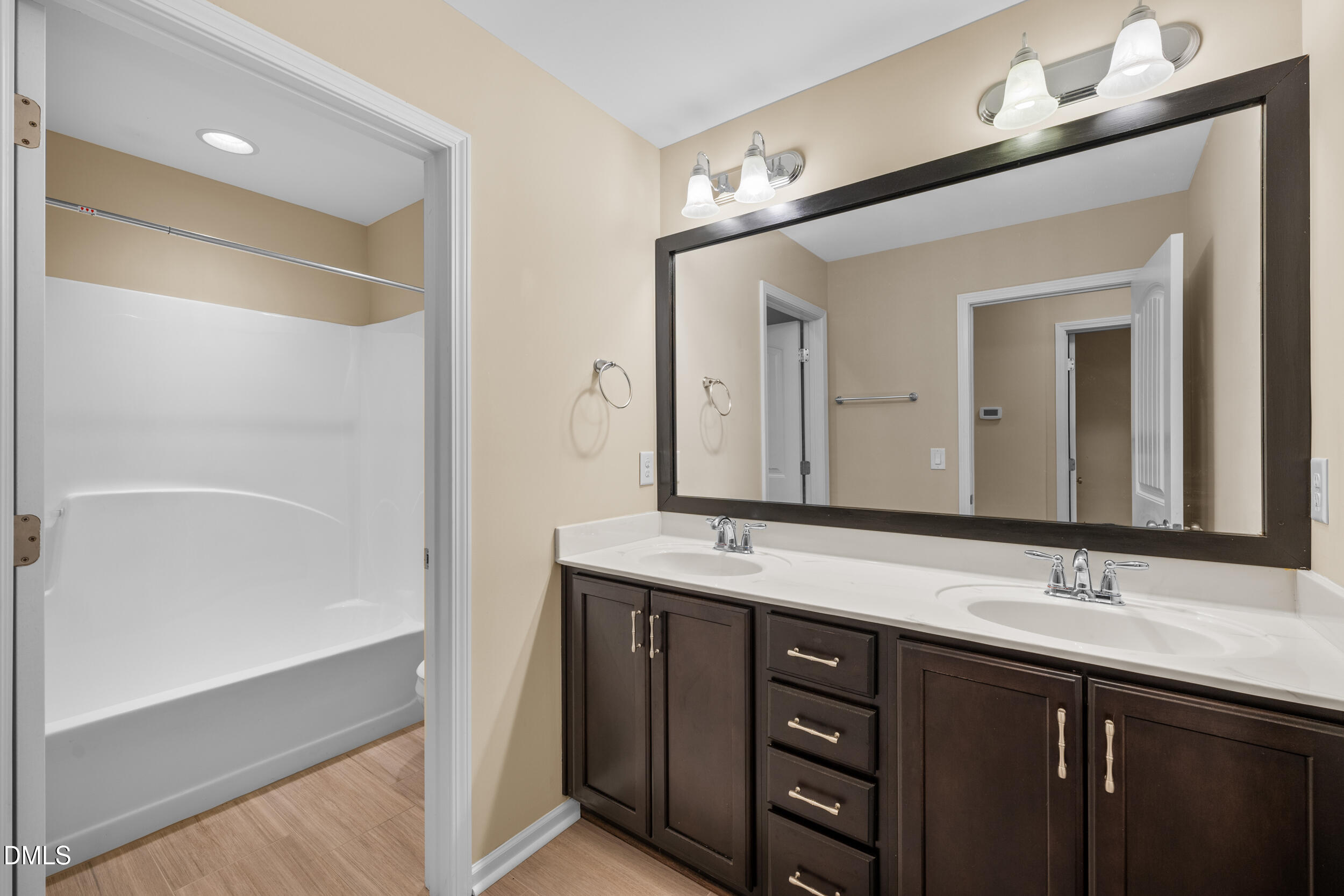 1217 Silver Beach Way Raleigh, NC 27606 - Photo 26 of 32 a bathroom with a double vanity sink a large mirror and a bathtub