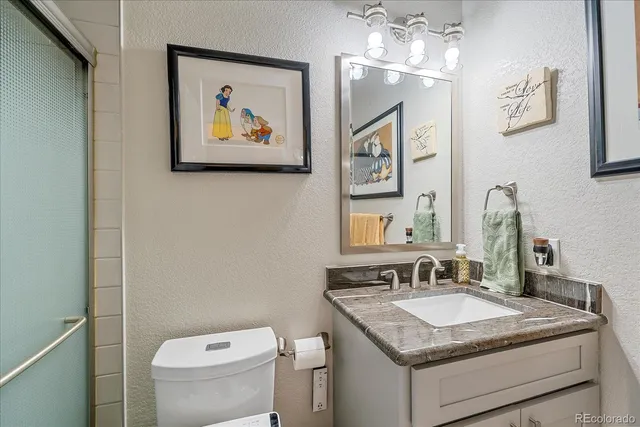 a bathroom with a granite countertop sink vanity and toilet