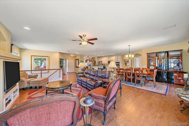 a living room with lots of furniture kitchen view and a large window