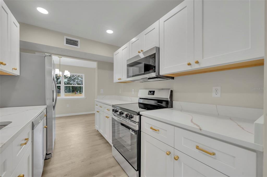 31201 Merry Road Tavares, FL 32778 - Photo 17 of 40 a kitchen with stainless steel appliances white cabinets and a stove top oven