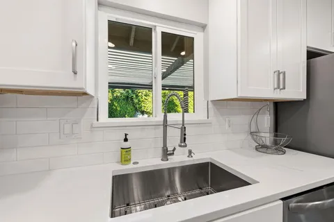 a kitchen with stainless steel appliances a sink a window and cabinets