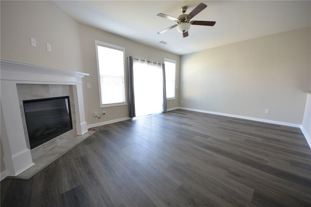 4722 Beacon Ridge Lane Flowery Branch, GA 30542 - Photo 9 of 24 an empty room with wooden floor fireplace and windows