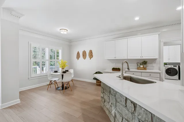 a kitchen with a sink a stove and white cabinets with wooden floor