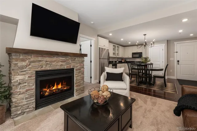 a living room with stainless steel appliances furniture a fireplace a flat screen tv and a fireplace