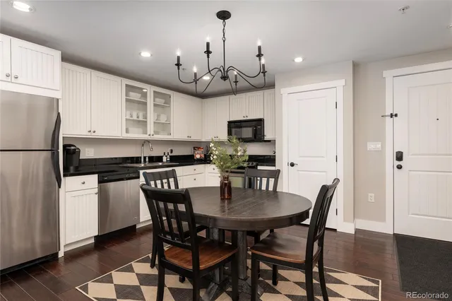 a kitchen with stainless steel appliances granite countertop a dining table chairs refrigerator and microwave