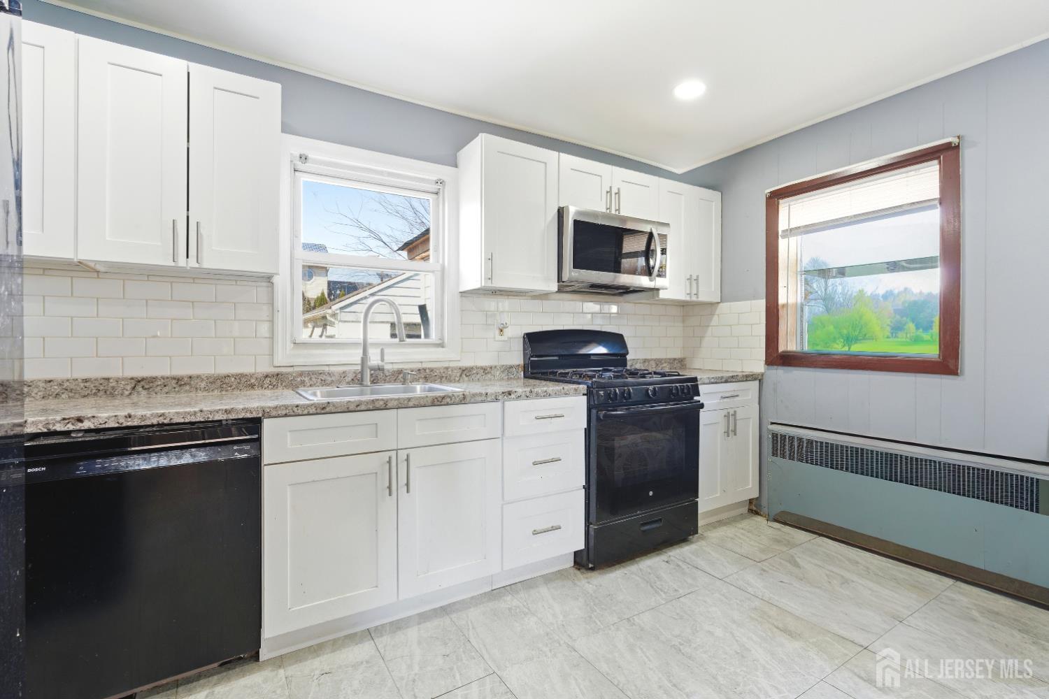 47 Spruce Street Port Reading, NJ 07064 - Photo 6 of 12 a kitchen with stainless steel appliances granite countertop a stove a sink and a microwave