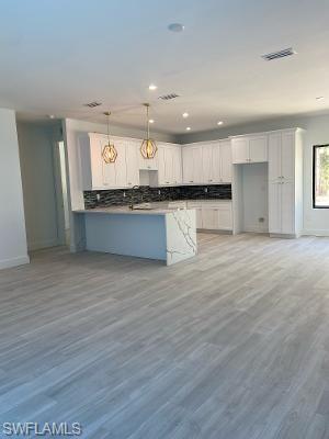 3651 29th Avenue Southwest Naples, FL 34117 - Photo 4 of 8 a open kitchen with kitchen island a sink white cabinets and wooden floor