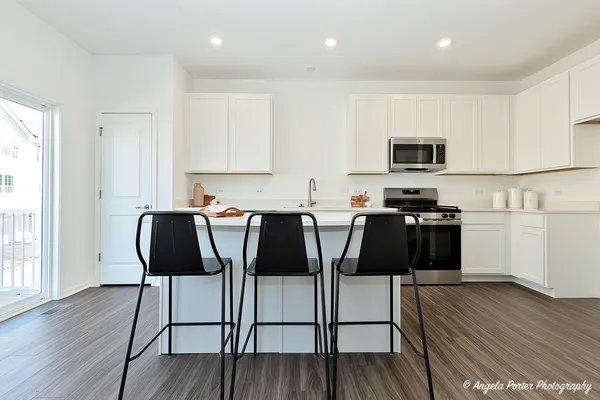 a kitchen with stainless steel appliances granite countertop a stove a sink a microwave a dining table and chairs with wooden floor