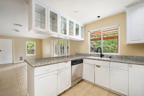 a kitchen with granite countertop stainless steel appliances white cabinets and a window