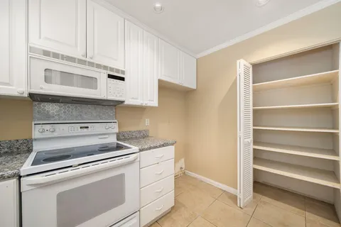 a kitchen with granite countertop white cabinets and white appliances