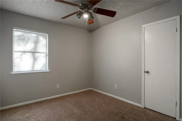 an empty room with a window and a fan