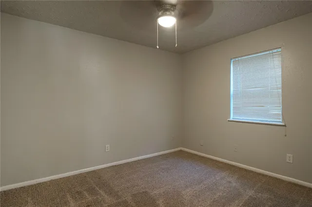 an empty room with a chandelier fan and windows